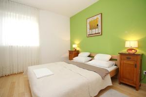 a bedroom with a white bed and a green wall at Apartment Krleza in Baška