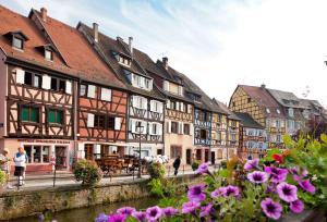 a group of buildings next to a river with flowers at hotelF1 Colmar Parc des Expositions in Colmar