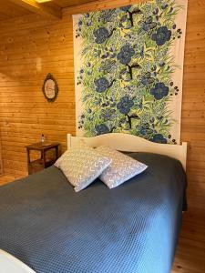 a bedroom with a bed with a blue comforter and a clock at Tamminiemen Lomamökit in Kustavi