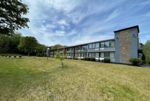 a large building with a grass field in front of it at Wingate by Wyndham Lake George in Lake George