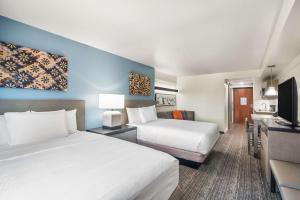 a hotel room with two beds and a flat screen tv at Hyatt House Sacramento-Midtown in Sacramento