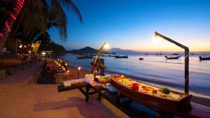 a boat filled with food on a beach at dusk at Wind Beach Resort in Ko Tao
