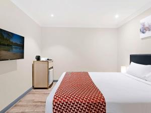 1 dormitorio con 1 cama y TV en la pared en BreakFree on Broadway Sydney, an Accor Hotel, en Sídney