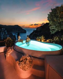 - un couple assis dans une baignoire avec le coucher du soleil dans l'établissement Hacienda Na Xamena, Ibiza, à Na Xamena