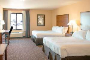 a hotel room with two beds and a desk at Expressway Suites of Grand Forks in Grand Forks