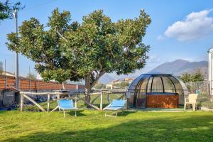 zwei Stühle und ein Gewächshaus in einem Garten mit einem Baum in der Unterkunft Baita Marina - Tramontana 30m mare in Ceriale