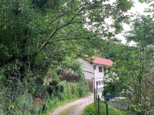 a dirt road next to a white house with trees at Casa Rural en Santa Cruz-Mieres in Bustiello