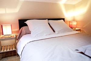 クレルモン・フェランにあるChez Maud et Jcのベッドルーム(白い大型ベッド、ランプ2つ付)