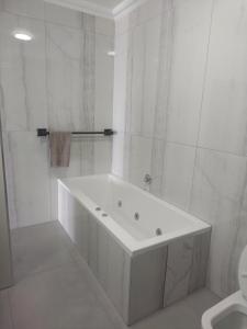 een witte badkamer met een bad en een toilet bij 504 Coral Reef in La Mercy
