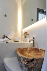 a bathroom with a stone sink with a mirror at Droufakos’ home, Lux seafront apartment w. View in Sifnos