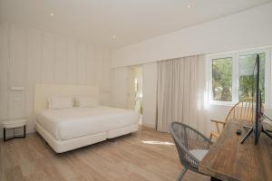 a bedroom with a white bed and a wooden table at Dune Beach CoLiving in Porto Santo