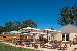 un patio con tavoli, sedie e ombrelloni di Domaine Mélusine - à 2km du Puy duFou ! a Les Épesses