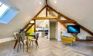 a living room with a dining room table and yellow chairs at Cosy appartement dans le Perche in Val-au-Perche