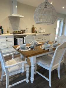 a kitchen with a wooden table and white chairs at The Pelican Room-converted Cart Lodge near airport in Horsham Saint Faith