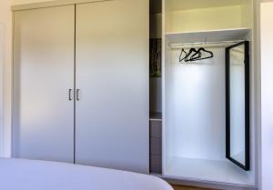 a bedroom with a white closet and a mirror at Lilly Pilly Cottage Margaret River in Margaret River Town