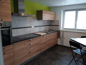 uma cozinha com armários de madeira e um lavatório em Le gîte des Kritter em Stosswihr