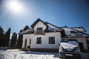 un'auto parcheggiata di fronte a una casa nella neve di Grand Villla Skyta a Vorokhta