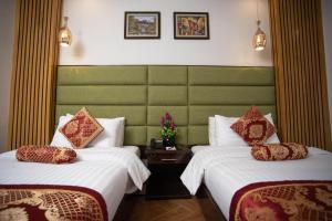 ein Hotelzimmer mit 2 Betten und einem grünen Kopfteil in der Unterkunft Hotel One Swat in Swat