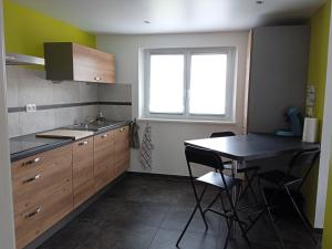 uma cozinha com um lavatório e uma mesa com cadeiras em Le gîte des Kritter em Stosswihr