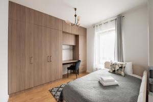 Mokotów Gaiety Place Apartment في وارسو: غرفة نوم بسرير كبير ومكتب