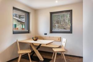 einen Tisch und Stühle in einem Zimmer mit zwei Fenstern in der Unterkunft Villa Lara Föhre in Kastelruth
