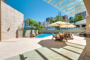 un patio con sillas y sombrillas junto a una piscina en K Hotel, en Goiânia