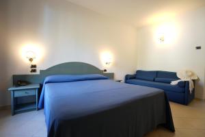 een slaapkamer met een blauw bed en een bank bij Hotel Scoglio Del Leone in Zambrone