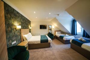 Habitación de hotel con 2 camas y sofá en Gwydyr Hotel en Betws-y-coed