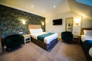 a hotel room with two beds and two chairs at Gwydyr Hotel in Betws-y-coed