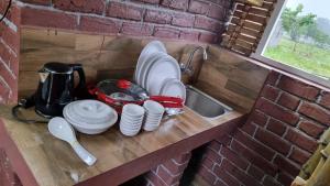 a kitchen counter with dishes and a sink in a brick wall at Woodside Haven in Auroville +14 photos