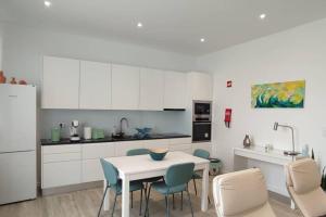 a kitchen with white cabinets and a table and chairs at Casa do Ilhéu in Vila Franca do Campo