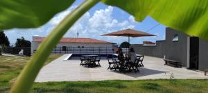 uma mulher sentada numa mesa debaixo de um guarda-chuva em Pousada Jardins - Mar Grande em Vera Cruz de Itaparica