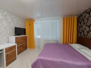 a bedroom with a purple bed and a tv at Стильні апартаменти Кравчука 10 LutskDoba in Lutsk