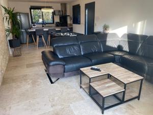 ein Wohnzimmer mit einem schwarzen Ledersofa und einem Tisch in der Unterkunft Luxury House Family’s in Carpentras