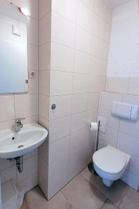a white bathroom with a toilet and a sink at Am Strand 2, PP innen in Zingst