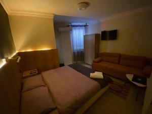 sypialnia z dużym łóżkiem i kanapą w obiekcie Hotel Lido w Prisztinie