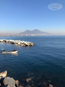 un pequeño barco en el agua cerca de una orilla rocosa en CLALE ROOMS, en Nápoles