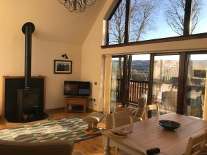 a living room with a table and a fireplace at Loch Aweside Forest Cabins in Dallavich
