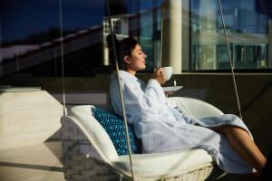 a woman sitting in a chair drinking a cup of coffee at Haubers Naturresort in Oberstaufen +50 photos