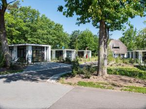 une rangée de maisons modulaires avec un arbre dans l'établissement TopParken - Recreatiepark Beekbergen, à Beekbergen
