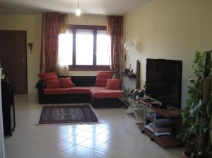 a living room with a red couch and a television at Sweet Sardinia Apartment R2968 in Elmas