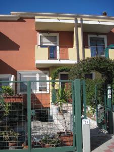 a green and white building with a fence at Sweet Sardinia Apartment in Elmas