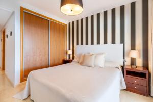 a bedroom with a large white bed and striped walls at Ceres Luxury Apartment in Rincón de la Victoria