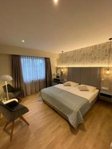a bedroom with a large bed and a chair at Hotel Strandhus in Cuxhaven