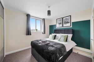 a bedroom with a bed with a green wall at Elegant Southampton Gems Sleeps 20 in Totton