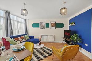 a living room with a blue couch and yellow chairs at Elegant Southampton Gems Sleeps 20 in Totton