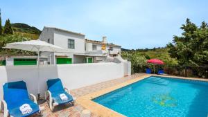 a villa with a swimming pool with two chairs and an umbrella at Cortijo los Valles Alozaina by Ruralidays in Alozaina