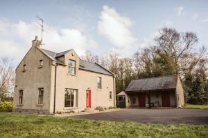 an old house with a red door in a field at Valley Lodge Enniskillen in Glenross