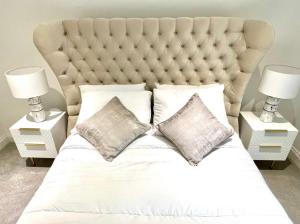 a white bed with two pillows and two lamps at Glasgow Central Luxurious Villa - Spacious and Contemporary. 13 mins Drv to Glasgow City Centre. 6 bedrooms, 5 Bathrooms, Double Garage, E Car Charging, Huge Garden. Excellent Location, Golf Course minutes away. Corporate Clients Welcome! in Newton Mearns