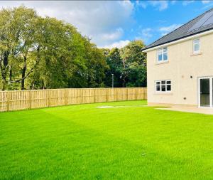 a large yard with a fence and a house at Glasgow Central Luxurious Villa - Spacious and Contemporary. 13 mins Drv to Glasgow City Centre. 6 bedrooms, 5 Bathrooms, Double Garage, E Car Charging, Huge Garden. Excellent Location, Golf Course minutes away. Corporate Clients Welcome! in Newton Mearns